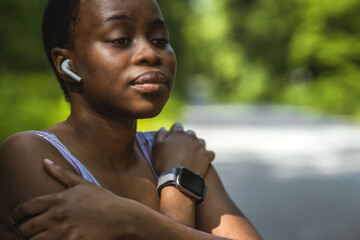 Active young black woman holding her shoulder in pain while exercising outdoors. Athlete suffering...