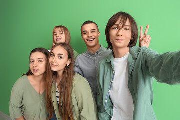 Fototapeta na wymiar Group of teenage students taking selfie on green background