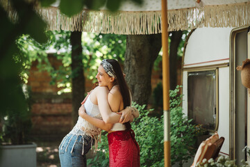 Happy hippie friends are embracing and having a good time together in camper trailer. Holiday, vacation, trip concept.