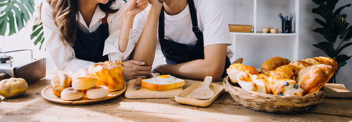 Young happy couple is enjoying and preparing healthy meal in their kitchen and reading recipes on the laptop.