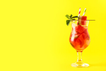 Glass of fresh watermelon lemonade with lime and mint on yellow background