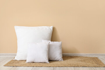 Fototapeta na wymiar White pillows on wicker mat near beige wall