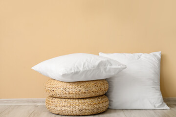 White pillows and wicker poufs on floor near beige wall