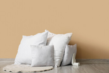 White pillows, feathers and rug near beige wall