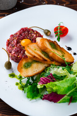 Fresh beef tartare with raw egg, fried bread, capers, French mustard, tomatoes, salad and sauce.