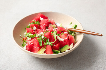 Bowl of tasty watermelon salad on light background
