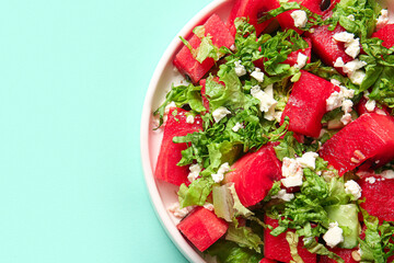 Plate of tasty watermelon salad on turquoise background