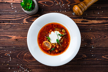 Solyanka soup with ham, meat, olives, tomatoes, sour cream, lemon, pickled cucumbers, onions and...