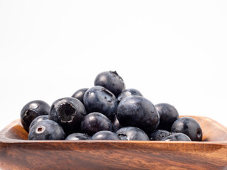 Ripe blueberries in a wooden bowl on a light background. blueberries close up