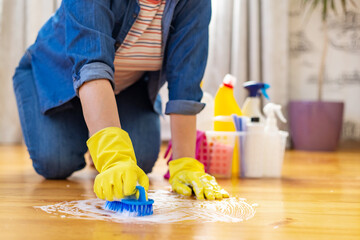 Woman in rubber gloves is using floor brush to cleaning floor