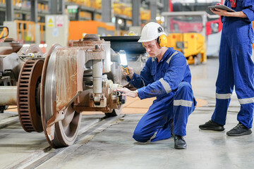 Engineers inspecting locomotive in railway engineering facility