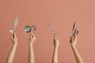 Female hands with baking utensils on pink background