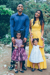 beautiful indian family standing and smiling in the park with trees and greenery