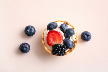 Tasty tartlets with whipped cream and berries on beige background