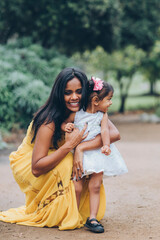 beautiful indian mother hugging her child daughter girl in the park with trees and greenery