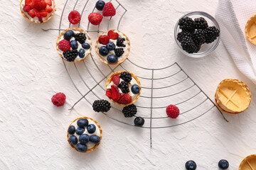 Naklejka na ściany i meble Stand of tasty tartlets with whipped cream and berries on white background