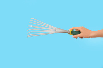 Woman with gardening rake on blue background