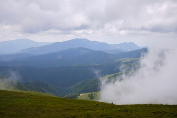 View on mountain valley in low clouds.Mountains in clouds. Carpathians mountains in Romania. Baiului Mountains trails.