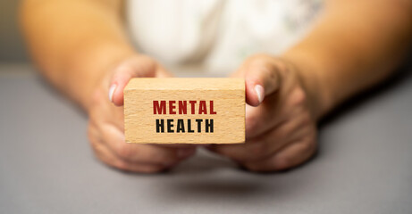 Mental health on wooden blocks in female hands. Emotional, psychological, and social well-being,...