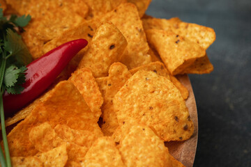 Traditional Mexican tortilla chips or spicy nachos with red hot pepper on the grey concrete background. Flat lay