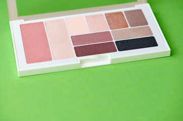 new palette with eye shadow and blush in different colors against green background
