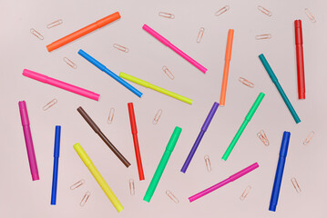 Colorful felt-tip pens and paperclips on pink background