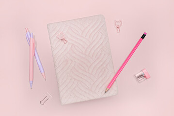 Notebook, pencil and pens on pink background