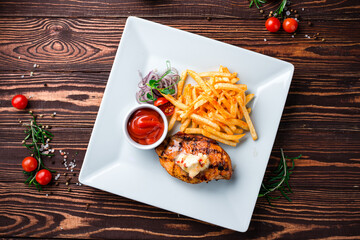 Fried chicken fillet with French fries, onion, cherry tomatoes and ketchup.