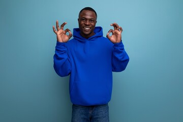 Naklejka premium portrait of a 30s black African man in a hooded sweatshirt laughing at his stupidity in a studio background with copy space