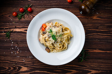 Pasta Tagliatelle with chicken, tomatoes, mushrooms, parmesan cheese and greens, dinner.