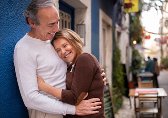 Happy Mature Couple Embracing And Laughing Standing On Street Outdoor