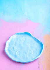 Blue empty handmade plate on color background