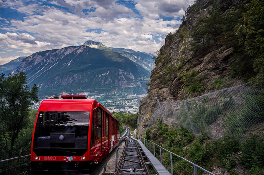 Red Swiss funicular from Sierre to Crans Montana, Valais Canton, Switzerland. Public transport cable car with scenic view over the city and mountain.