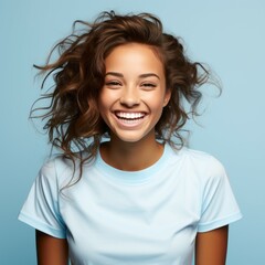 Portrait of a smiling young adult African woman with curly brown hair on a blue background. Happy...