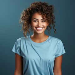 Fototapeta premium Portrait of a smiling young adult Latin woman with wavy brown hair on blue background. Happy young Latin American woman with smile in blue shirt with curly hair. Cheerful woman with shiny white teeth.