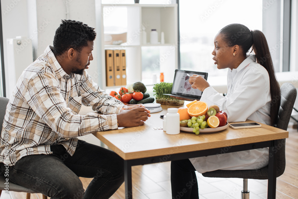 Wall mural african american specialist in nutrition holding tablet with gastrointestinal tract on screen while 