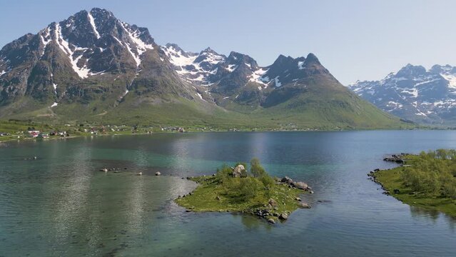 un îlot vert au centre d'un lac bleu entouré de montagne enneigée