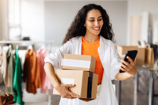Fashion Designer Messaging On Cellphone Posing With Boxes In Store