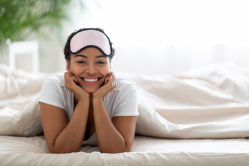 Beautiful Young Black Woman With Sleep Mask On Head Relaxing On Bed