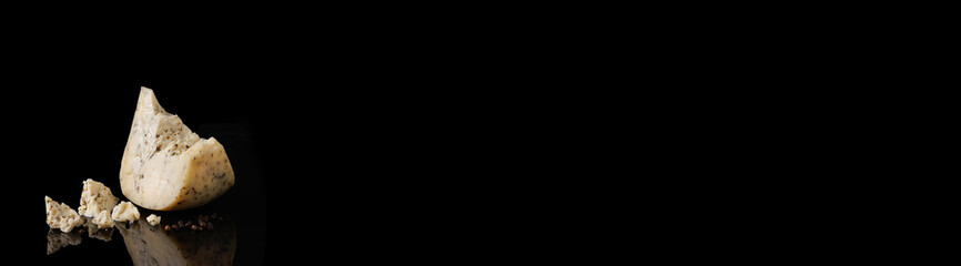 Banner. Hard cheese on a black background with a reflection. Monterey with pepper. With black pepper