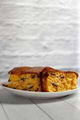 Two slices of English cake are placed in a dish on top of a white wooden table.