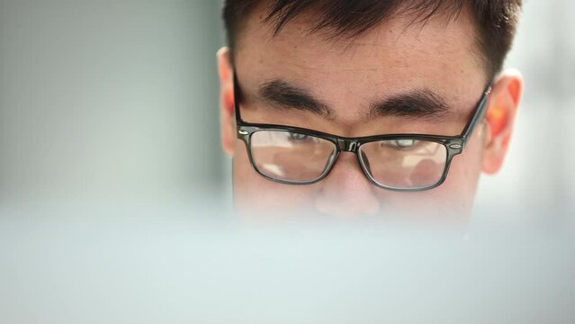 man in shirt and glasses using laptop at work, investor pondering complex decision.