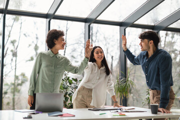 Multicultural Colleagues Team Celebrates Achievement with High Five In Office