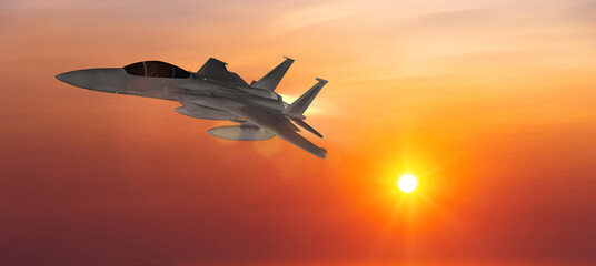 Military aircraft flying on a sunset sky background