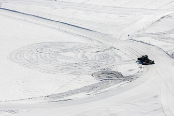 Modern snowcat ratrack with snowplow snow grooming machine preparing ski slope piste hill at alpine...