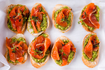 Bruschetta with salmon, avocado and microgreens on a white.