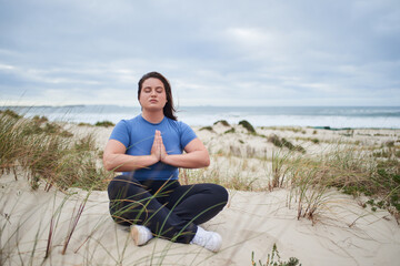 Fototapeta na wymiar Plus size woman meditating near the ocean in the morning
