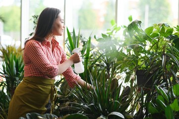 Woman florist working at her flower shop standing surrounded by plants