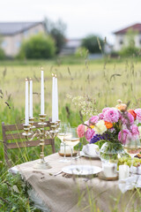 Summer sunset, romantic date outdoors in meadow, marriage proposal. Romantic sunset dinner in the field. Table honeymoon set for two with luxurious food, glasses of champagne drinks in a restaurant.