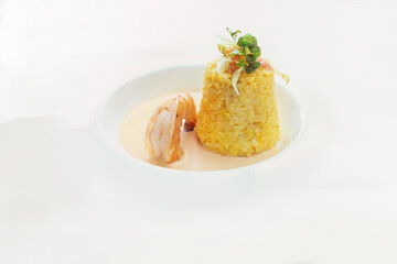 Saffron risotto in a cone shape with herb and vegetable garnish, a large prawn and crustacean sauce in a modern white plate, delicious seafood dish, copy space, selected focus